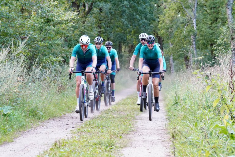 Een groep fietsers op een zandpad in een bos
